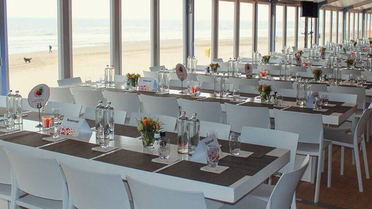 Gedekte tafels voor personeelsfeest bij feestlocatie Beachclub O in Noordwijk aan Zee.